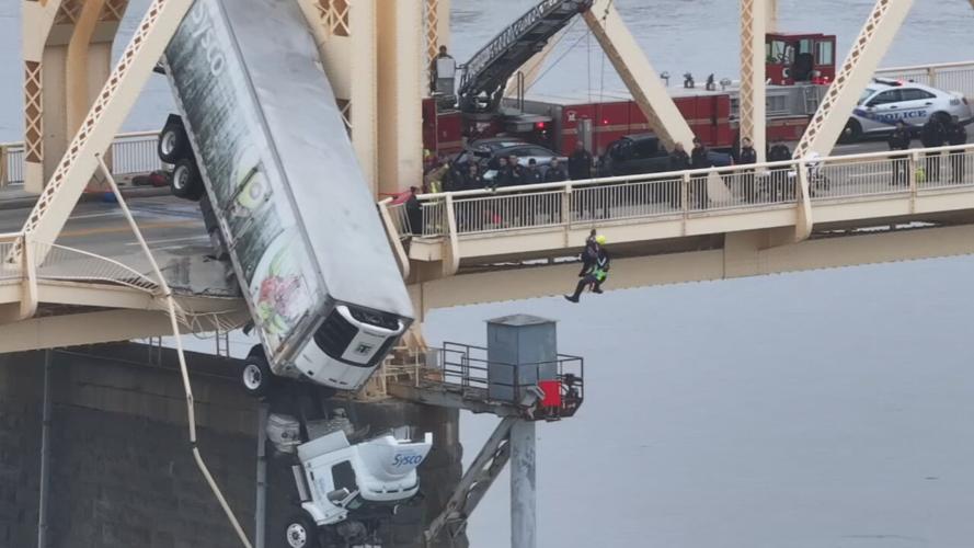 Crews pull driver from semi dangling from 2nd Street Bridge