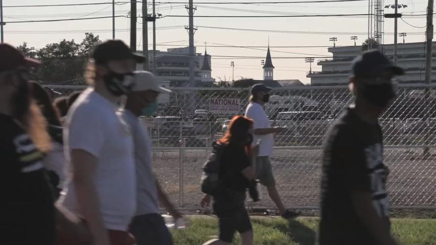 Protesters march with Twin Spires in the background