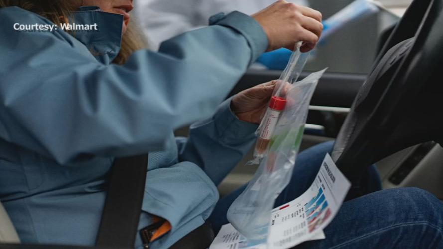 A woman handles a COVID-19 test at a Walmart site