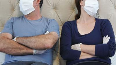 Couple in bed wearing masks