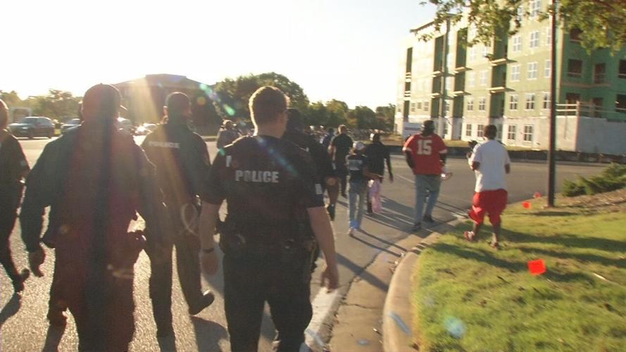 Police walk behind crowd marching during outside AG Daniel Cameron's office in Louisville 9/18/20