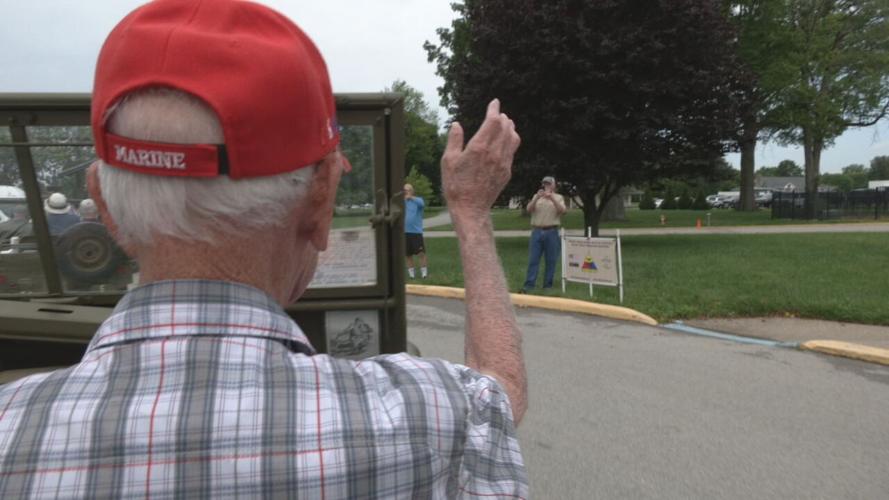 WWII veteran Damon Hawkins waves as he rides in a jeep around Seneca Park