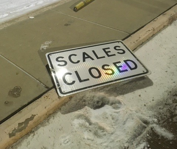 Scales Closed Sign on ground after car crashes into scale house gate