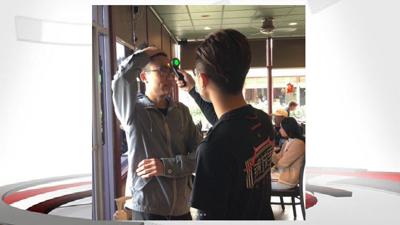 Restaurant worker takes customer temperature