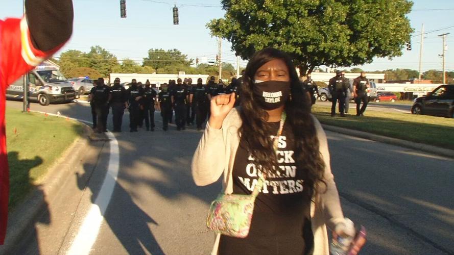 Protesters marches with police behind her during rally outside AG Daniel Cameron's office in Louisville 9/18/20