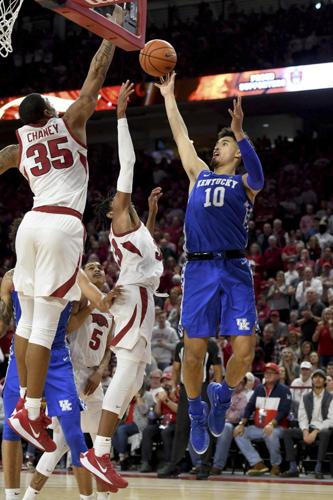 Kentucky guard Johnny Juzang (10) pulls up for a jump shot over Arkansas defenders Jimmy Whitt Jr. (33) and Reggie Chaney