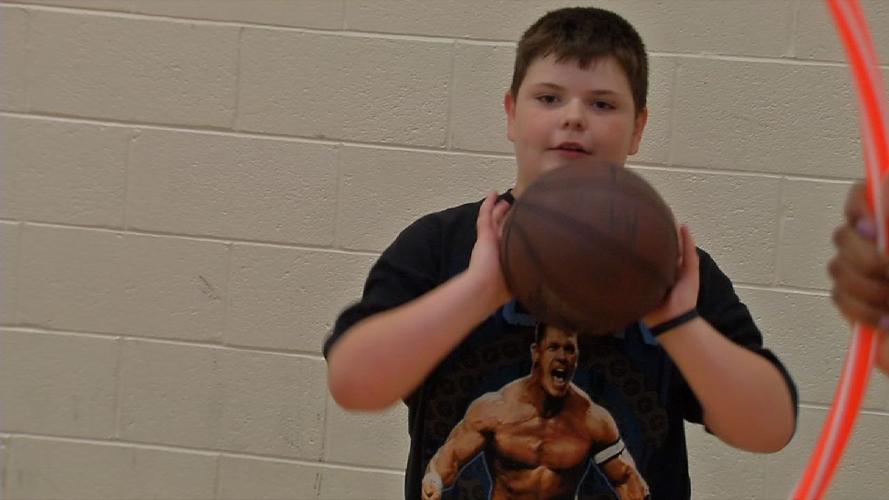 Kid passing ball through hoop at Luke Hancock's basketball camp