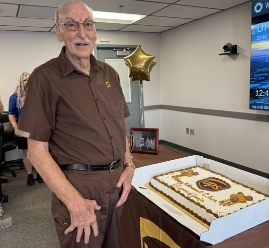 Cleveland Francis poses next to UPS retirement cake