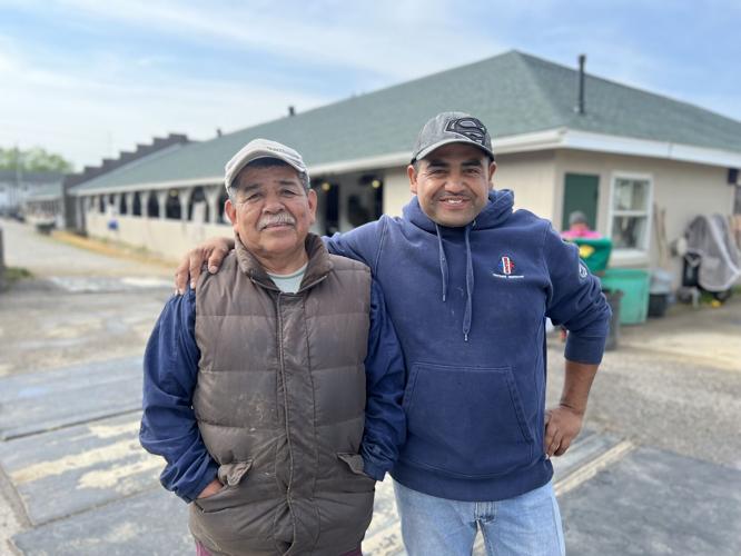 Horse groom Flores smiles alongside colleague on backside at Churchill Downs