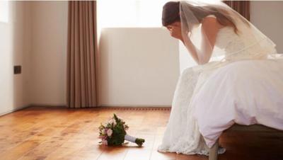 Woman in wedding dress with head in hands