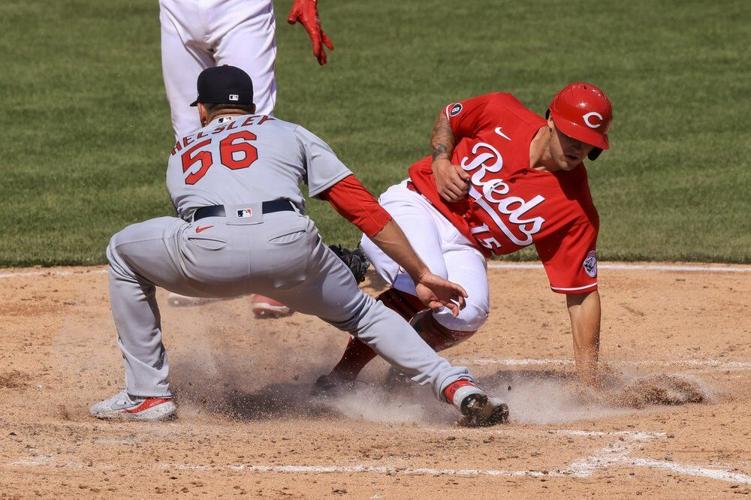 Cincinnati Reds' Nick Senzel, right, scores a run ahead of the tag