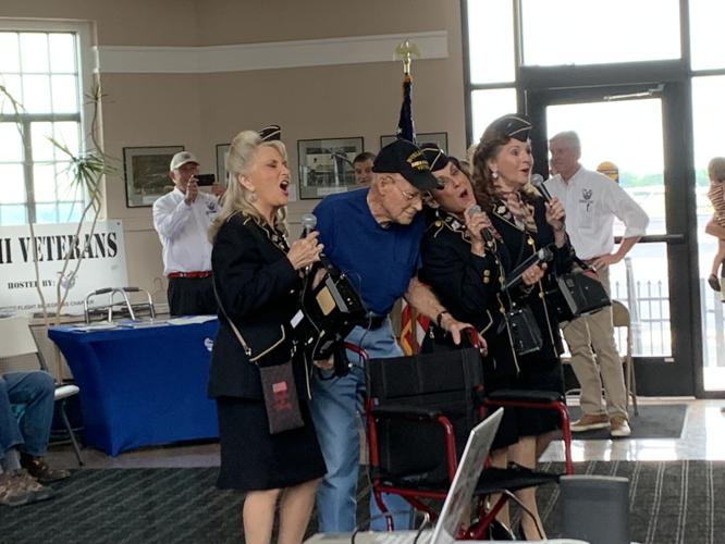 A World War II veteran enjoys the company of Ladies of Liberty, a female singing group