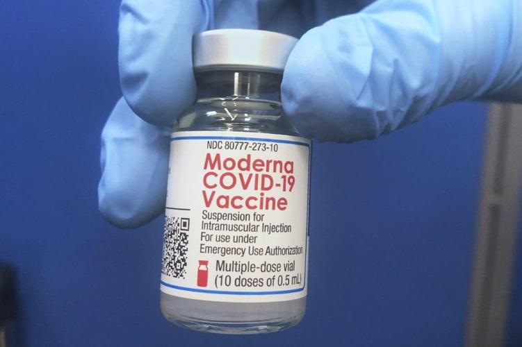 Vial of Moderna COVID-19 vaccine being held.jpeg