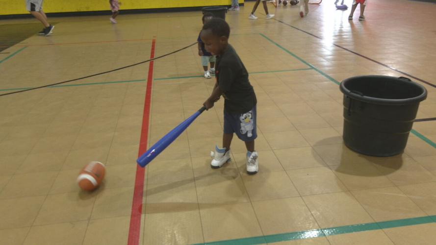 Kid plays with ball and bat at Park Hill Community Center Field Day