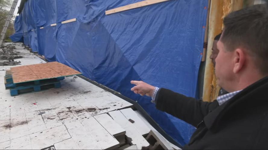 Mark Lichtefeld points to warehouse damage caused by severe storms
