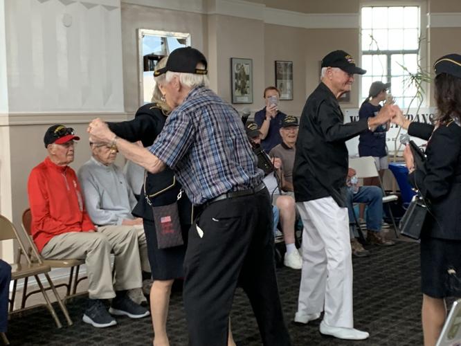 A World War II veteran enjoys the company of Ladies of Liberty, a female singing group