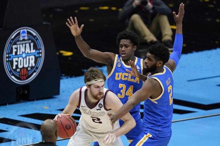 Gonzaga forward Drew Timme, left, dribbles around UCLA guard David Singleton
