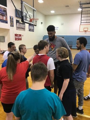 Trey Moses works with a group of children on the basketball court
