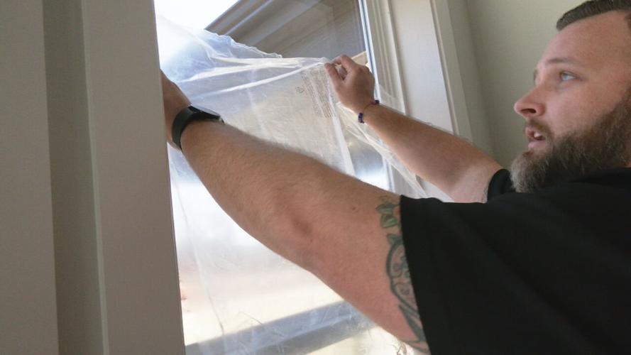 Jamason Welker with Bryant Heating and Cooling seals windows with plastic cover.
