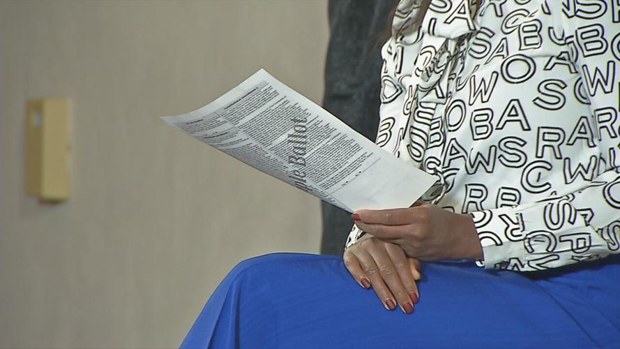 A woman reads from a sample ballot during the "Know the Issues, Own the Vote" Symposium