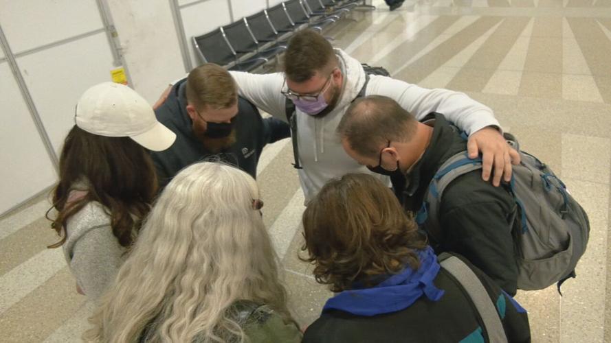 Volunteers pray before boarding flight to Poland to help refugees