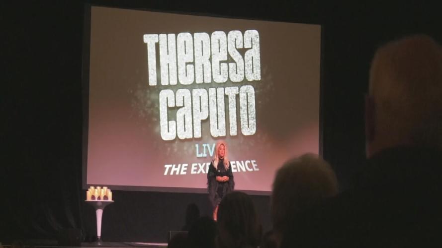 Theresa Caputo in front of screen during performance