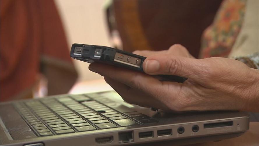 Woman with cellphone next to laptop