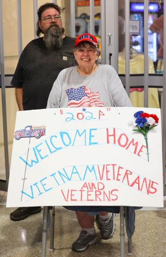 Woman holds up Welcome Home Vietnam Veterans sign at Honor Flight.JPG