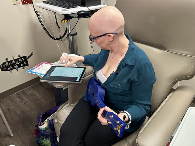 Gillian Hollis plays a guitar while receiving treatment.jpg