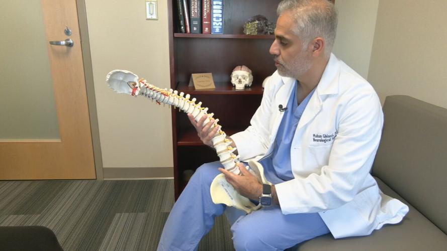 DR. GHIASSI HOLDS SPINE DIAGRAM