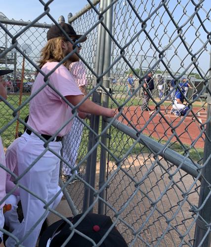 Landis Sims looks through dugout fence during game