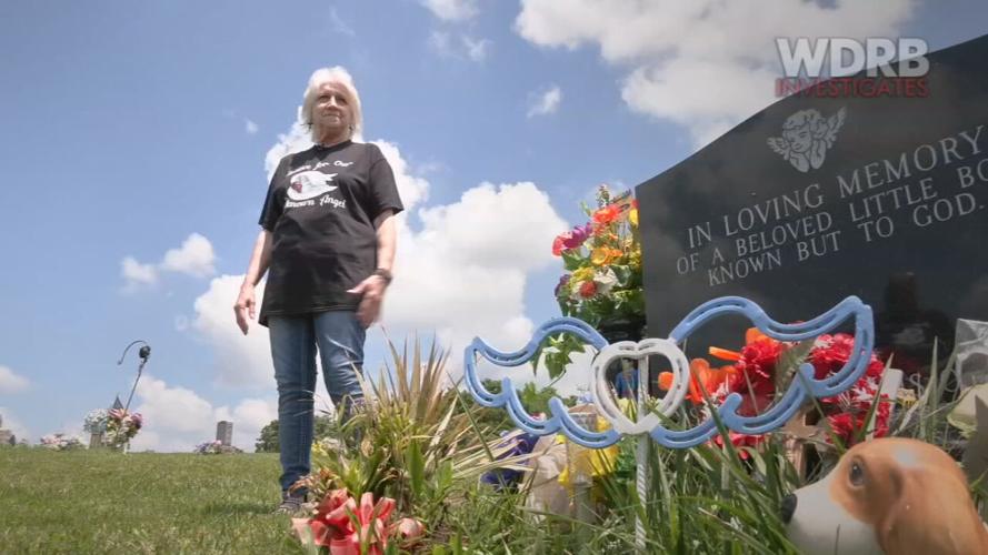 Janet Irk stands beside the grave of an unidentified boy, believed to be 5 years old, found dead in a suitcase in Washington County, Indiana