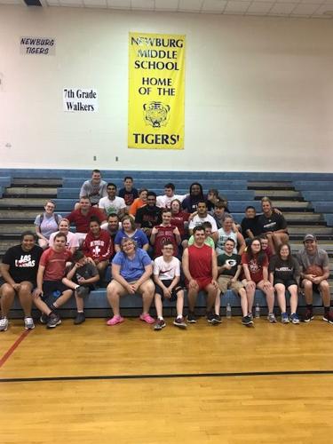 Trey Moses poses with a group of children in a school gym