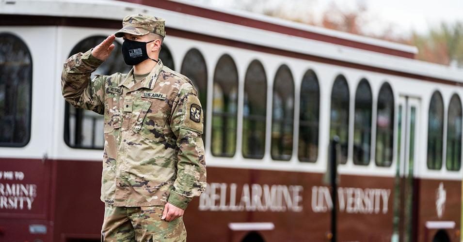 Service man salutes in front of Bellarmine bus