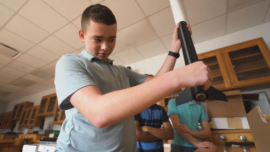 A student with a rocket designed by Louisville Rocketry