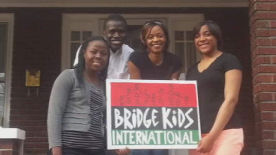 Members of Bridge Kids international hold a sign with the nonprofit's logo