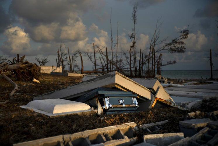 A coffin peaks out of a grave, in aftermath of Hurricane Dorian