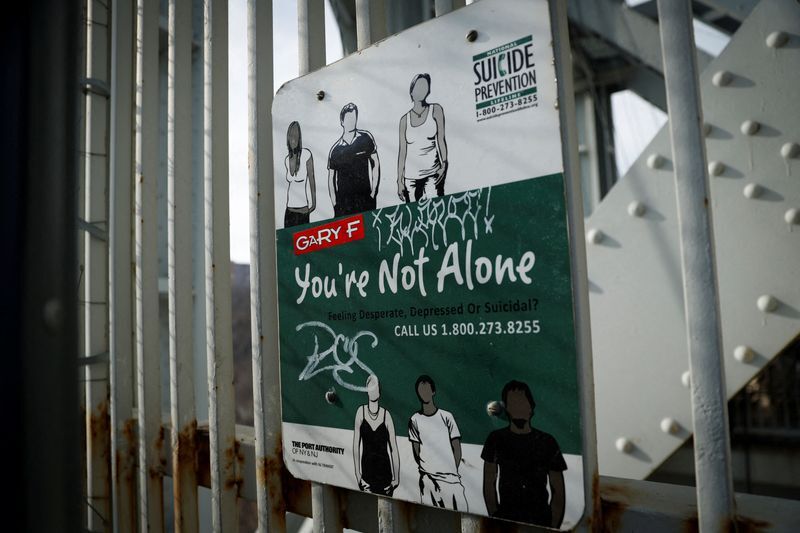 Suicide prevention sign is pictured on protective fence on the walkway of the George Washington Bridge in New York