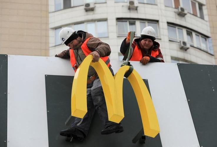 Workers remove the logo signage from a restaurant of McDonald's in Almaty