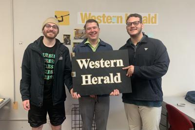 Collin hold a Western Herald sign on his last day in the office with Ben Epstein and Travis Leonardi.