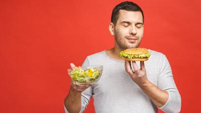 Man choosing between healthy food and junk food