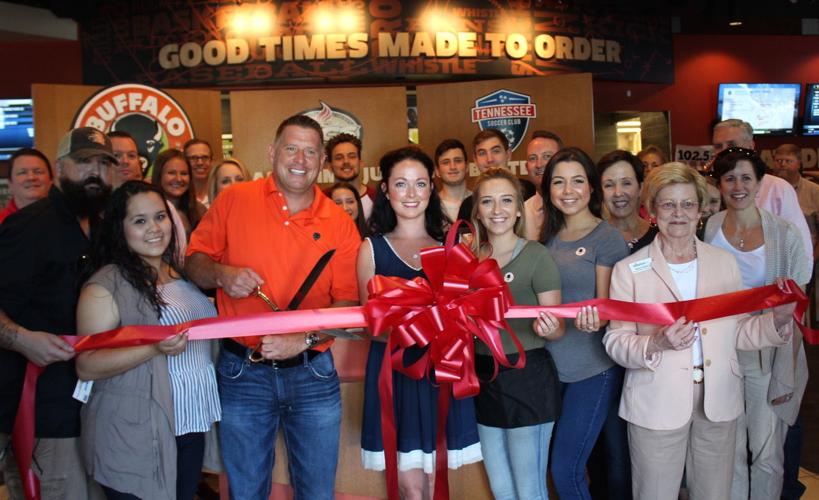 Buffalo Wings & Rings owner Mark Cross (with scissors) and General Manager Candace Dunn (center) with other team members and Williamson Inc. members.