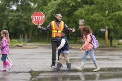 Smiling crossing guard helps students safely cross street