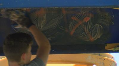 A.J. Verhey scrubs away graffiti from a playground in Frankfort