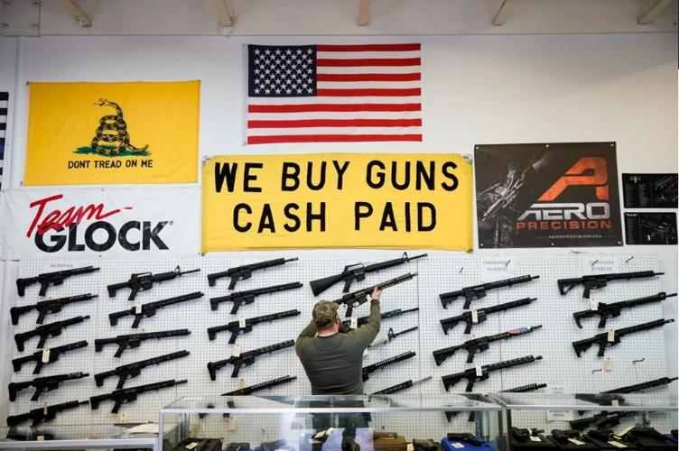 A salesperson takes an AR-15 rifle off the wall at a store in Orem, Utah, on March 25, 2021.