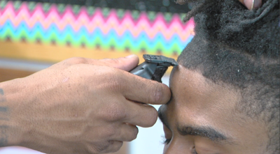 Student recieving haircut by Dr. Ryan James Reed