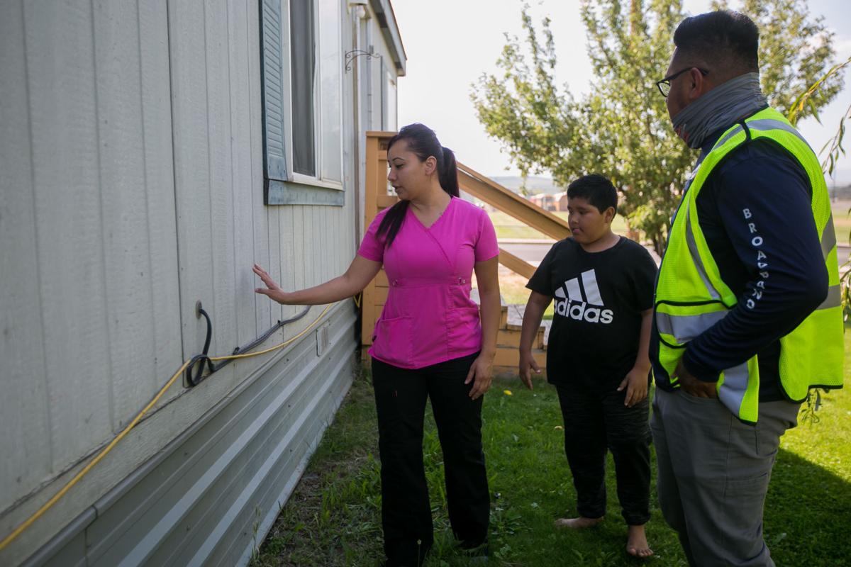 Veronica Gonzalez shares the layout of her living room with Alfonso Duran, an employee of Washington Broadband, to determine a good location for running an internet cable through her home in COwiche, Wash., on Monday, Aug. 17, 2020. 